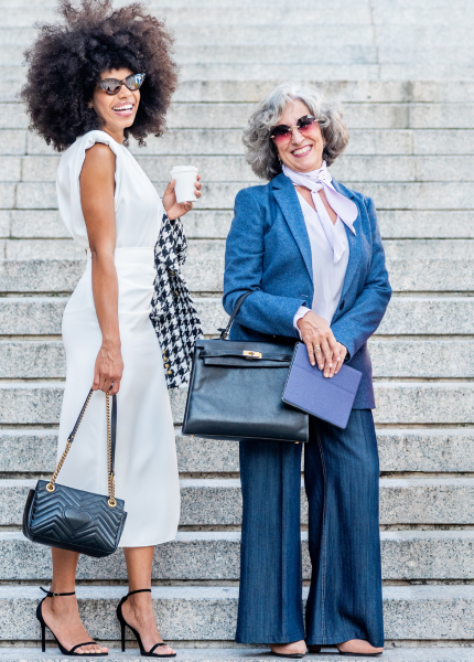 Two individuals standing on steps, one holding a coffee cup and the other carrying a briefcase and a book, symbolizing the diverse lifestyles of digital nomads and expats.