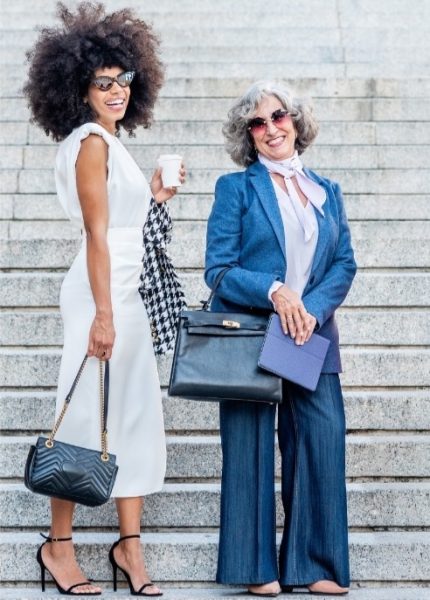 Two individuals standing on steps, one holding a coffee cup and the other carrying a briefcase and a book, symbolizing the diverse lifestyles of digital nomads and expats.